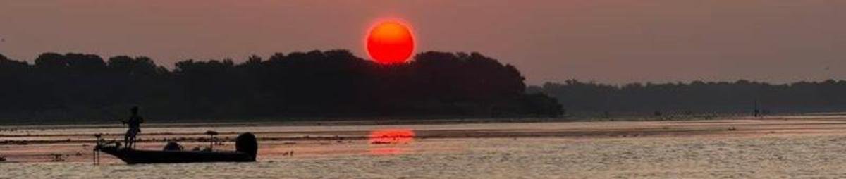 A bass boat on calm water at sunset